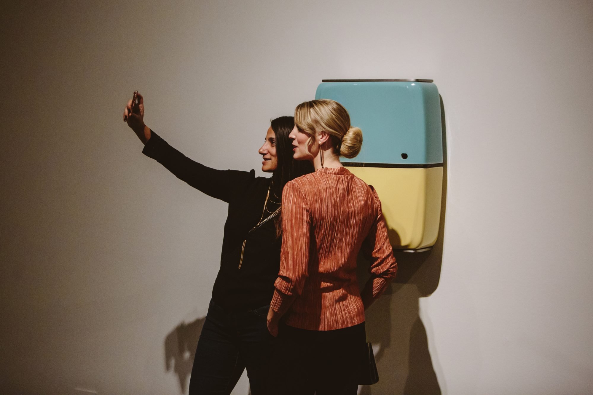 Visitors take a selfie with items on display in ExtraOrdinary Objects at Glenbow.