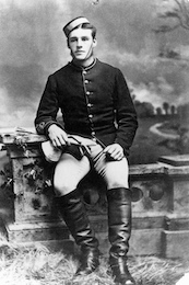 Fred Bagley poses leaning against a fence post in an antique photo in his Mounted Police uniform