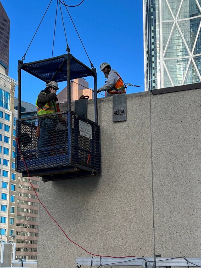 The construction crew inspects the original concrete panels on the building, ahead of removing them.