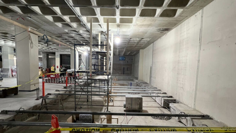 A photo of the exposed interior of the opened gallery space. Teams cut through the concrete floor to create more space.