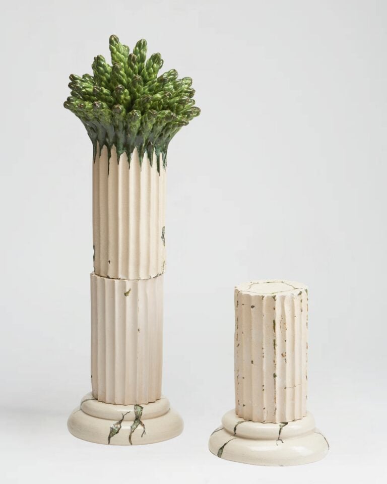 Asparagus tips emerge from the top of a ceramic column.