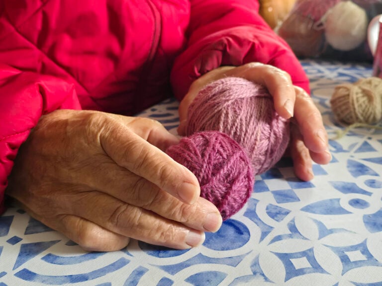 Two hands hold warm coloured balls of wool yarn