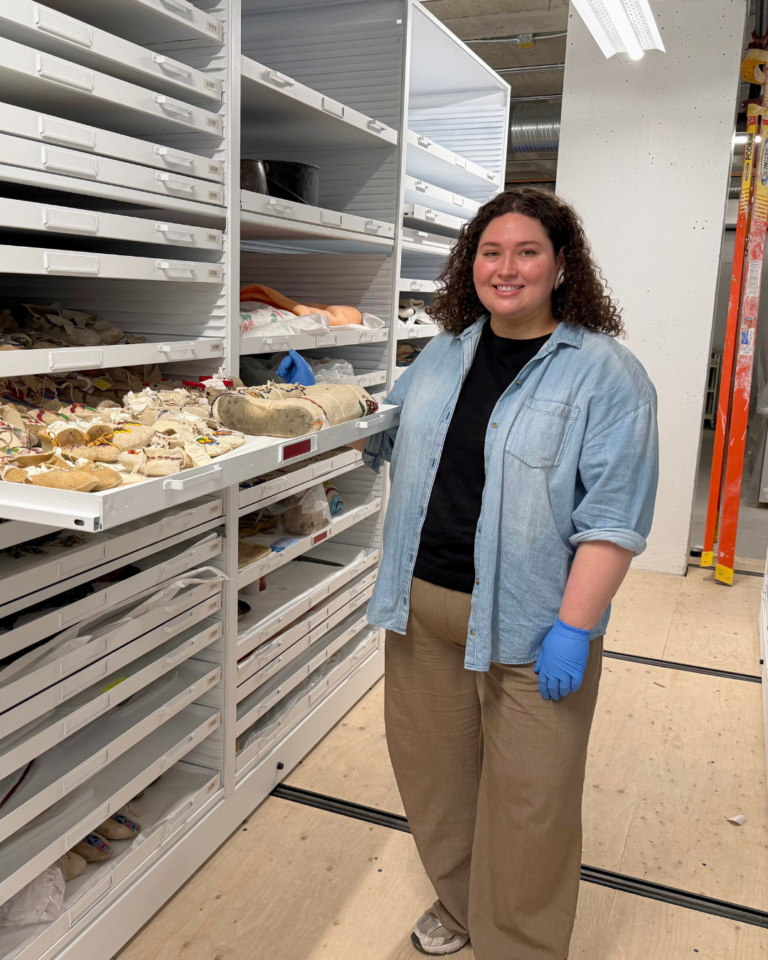 A women stands next to an open drawer in museum storage.